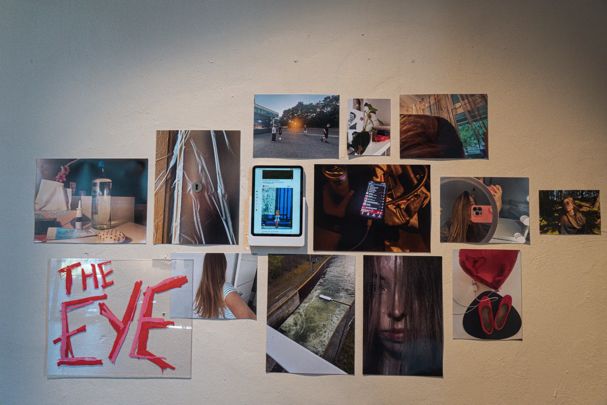 Photographs and a small screen arranged together on an exhibition wall.