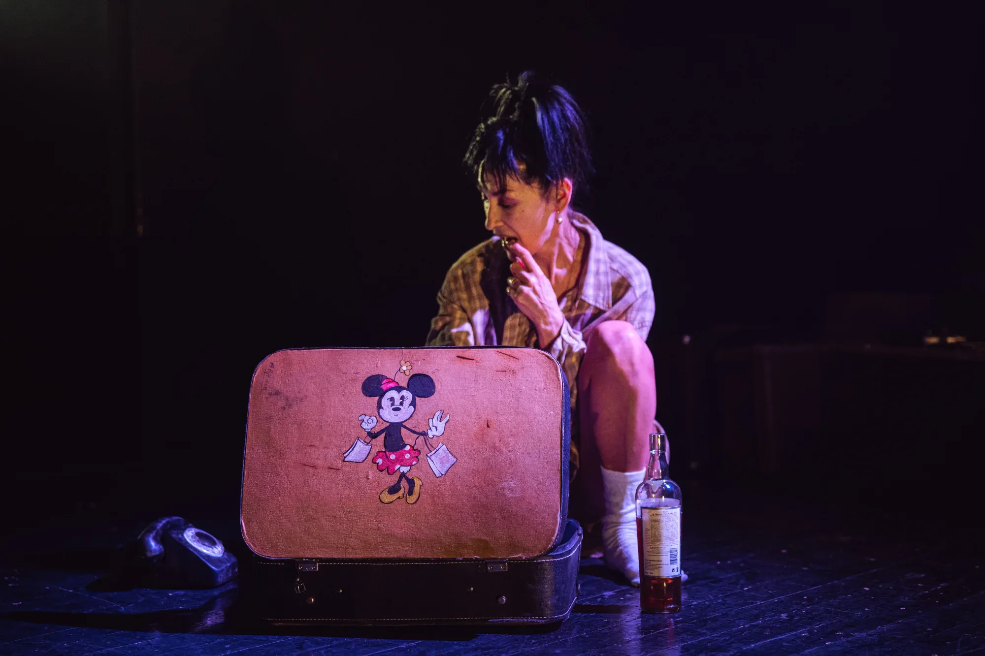A scene from the production: a young woman on a suitcase.