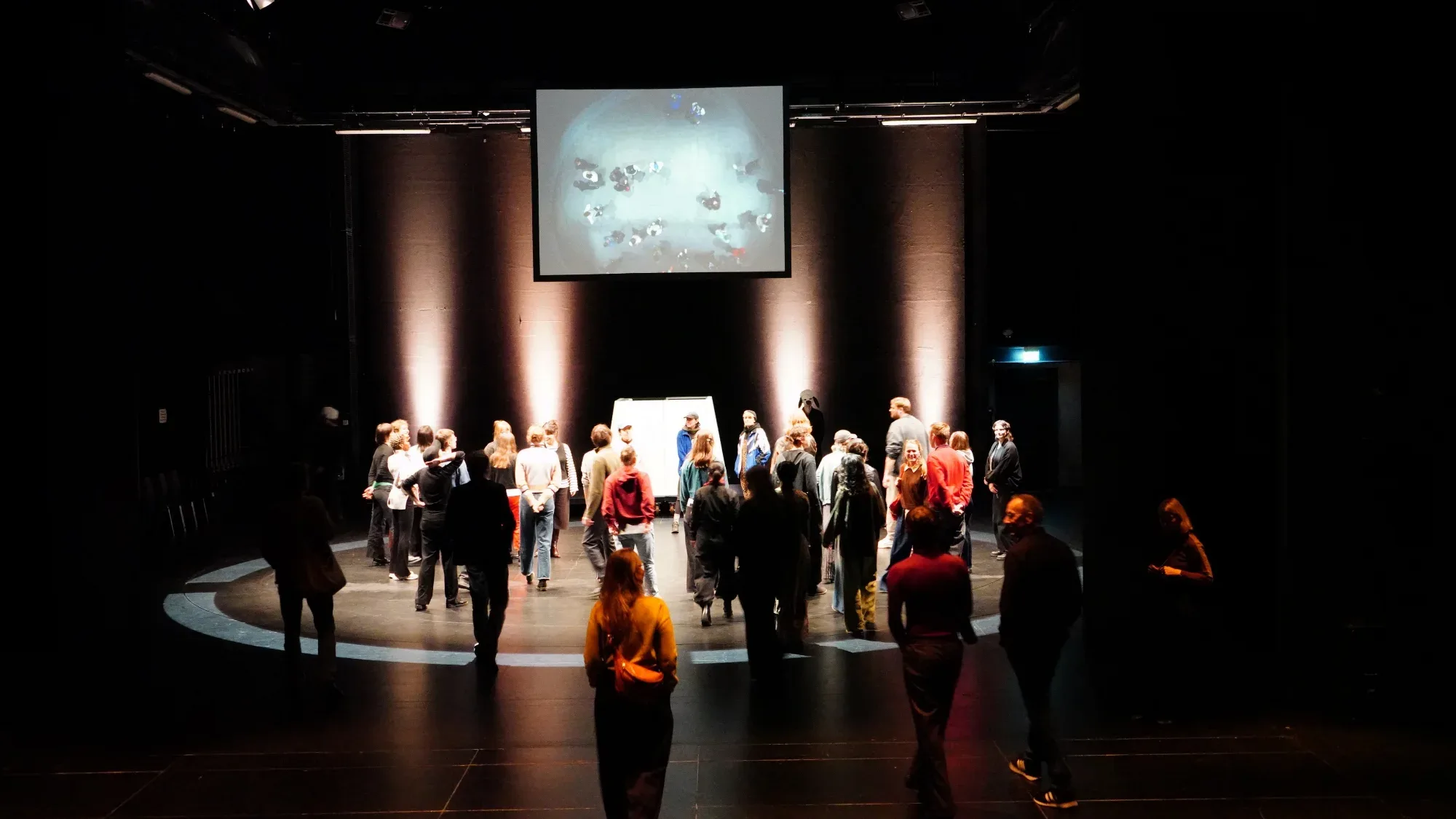 Spectators gather in a circle of light.