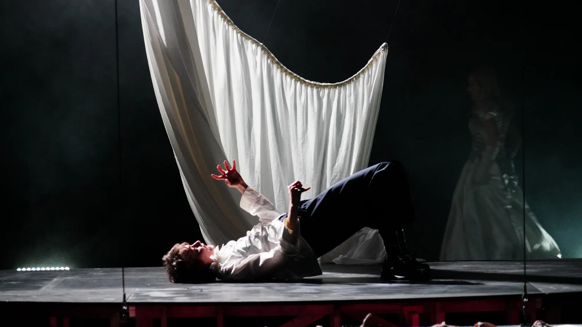 A performer on the floor beneath a white sheet of fabric.