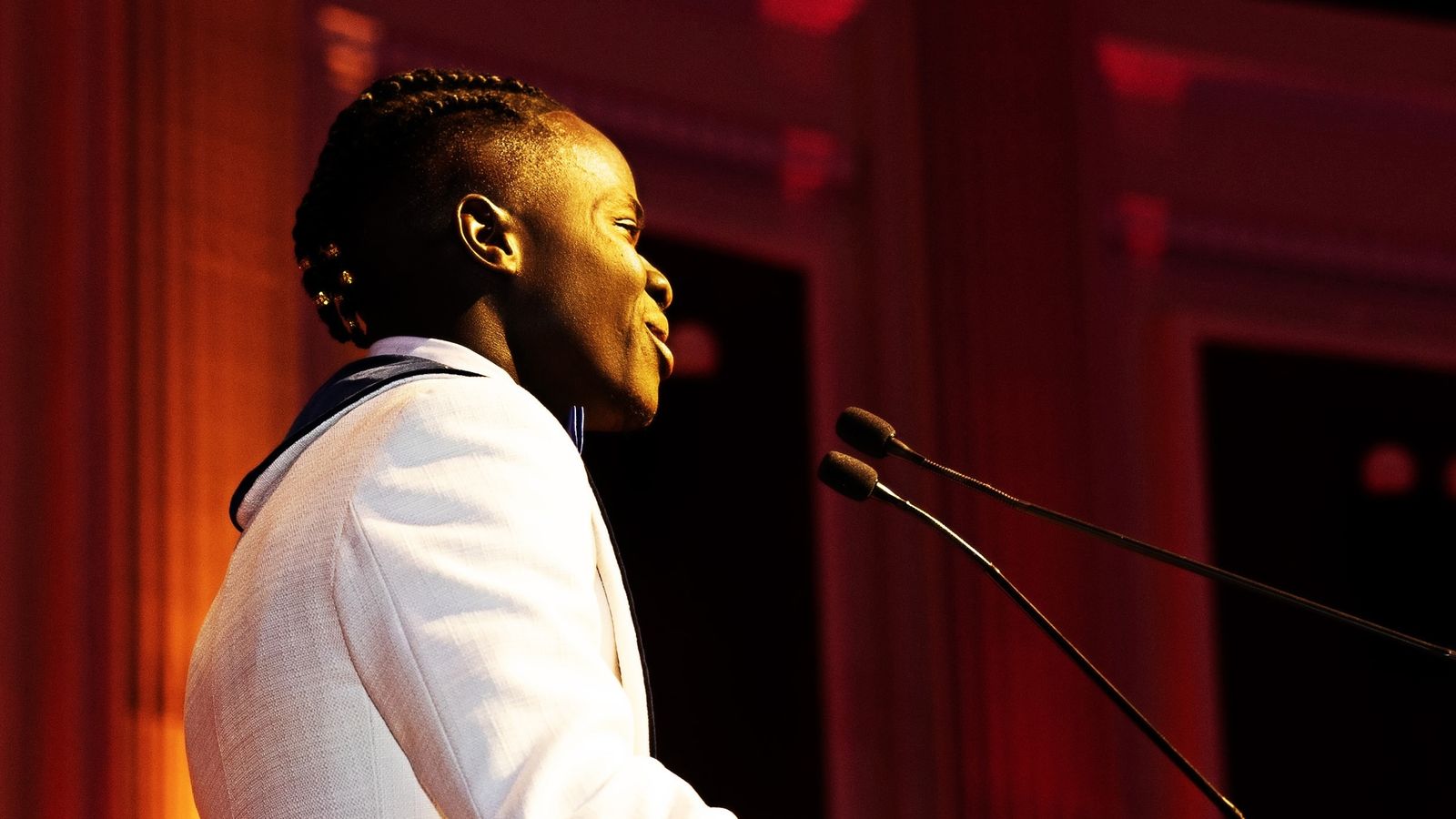 a man is standing on a stage with a microphone in his mouth .