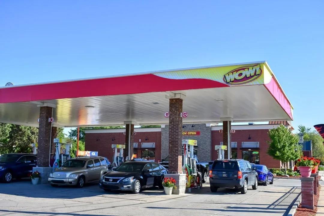 WOW station canopy with a red and yellow wave fascia over cars at the pumps