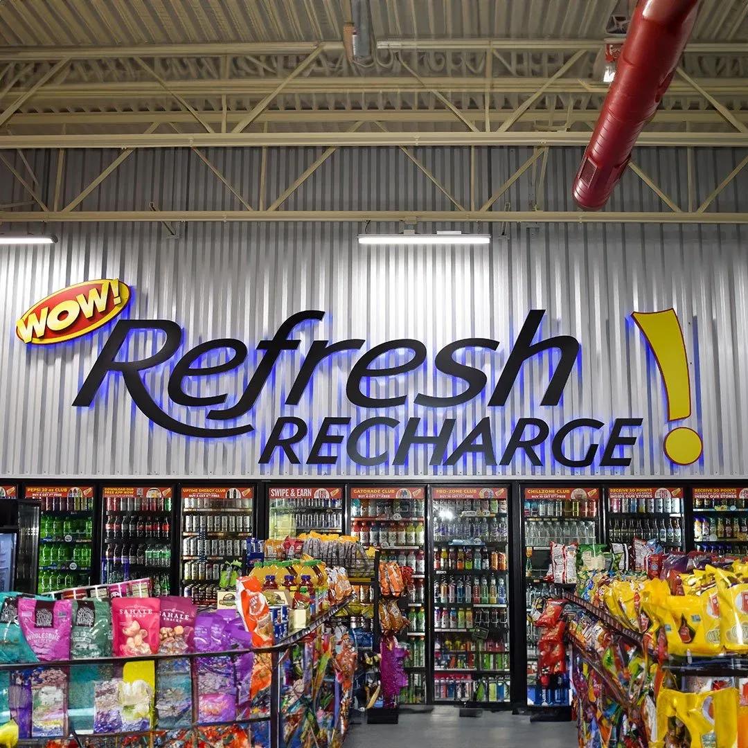 Refresh Recharge sign with a WOW logo above the drink coolers inside a store