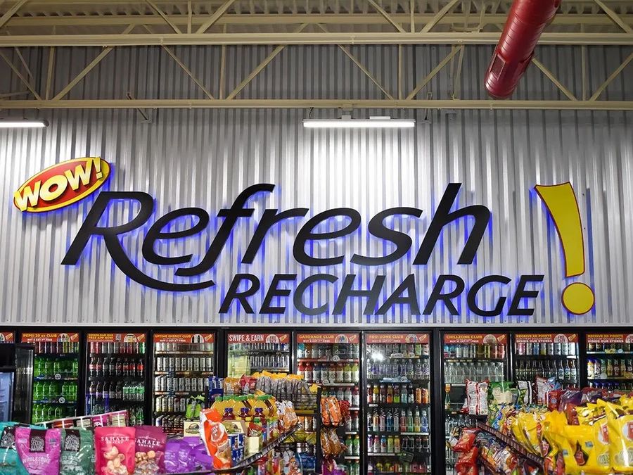 Refresh Recharge sign with a WOW logo above the drink coolers inside a store