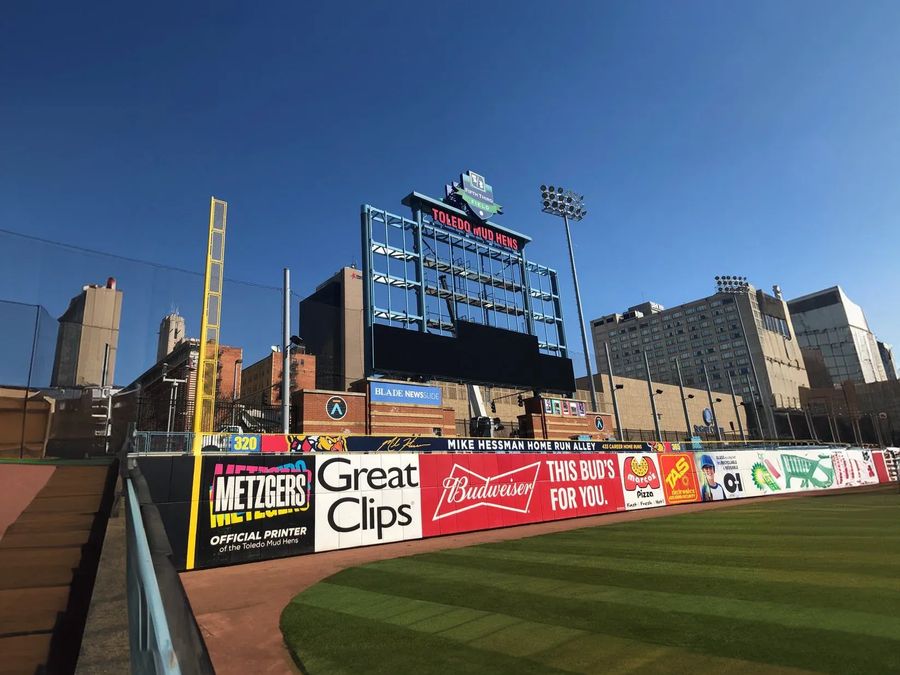 Wide view of a ballpark outfield with the video scoreboard and signs along the outfield wall