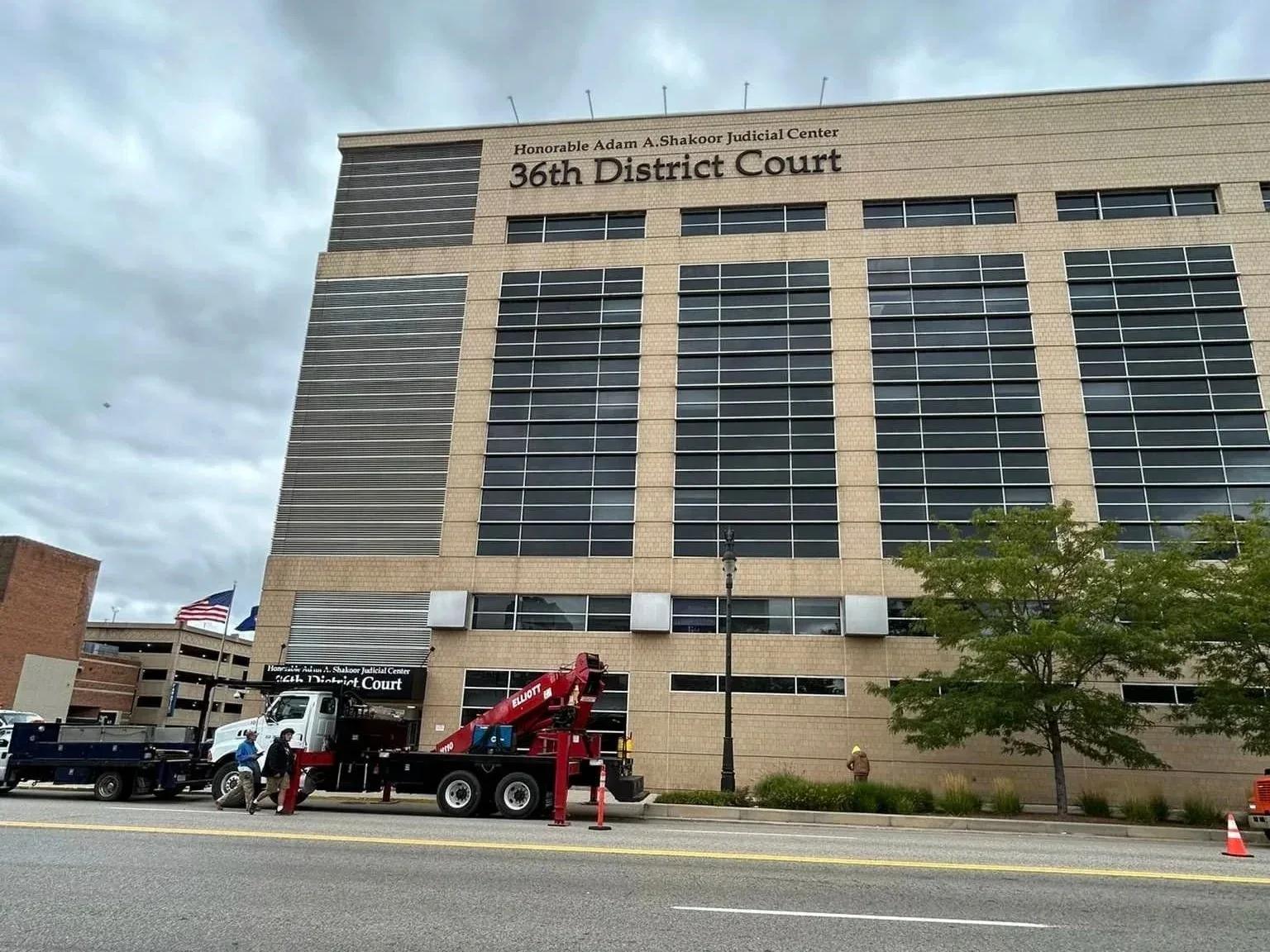 Red crane truck parked at the curb in front of the 36th District Court building
