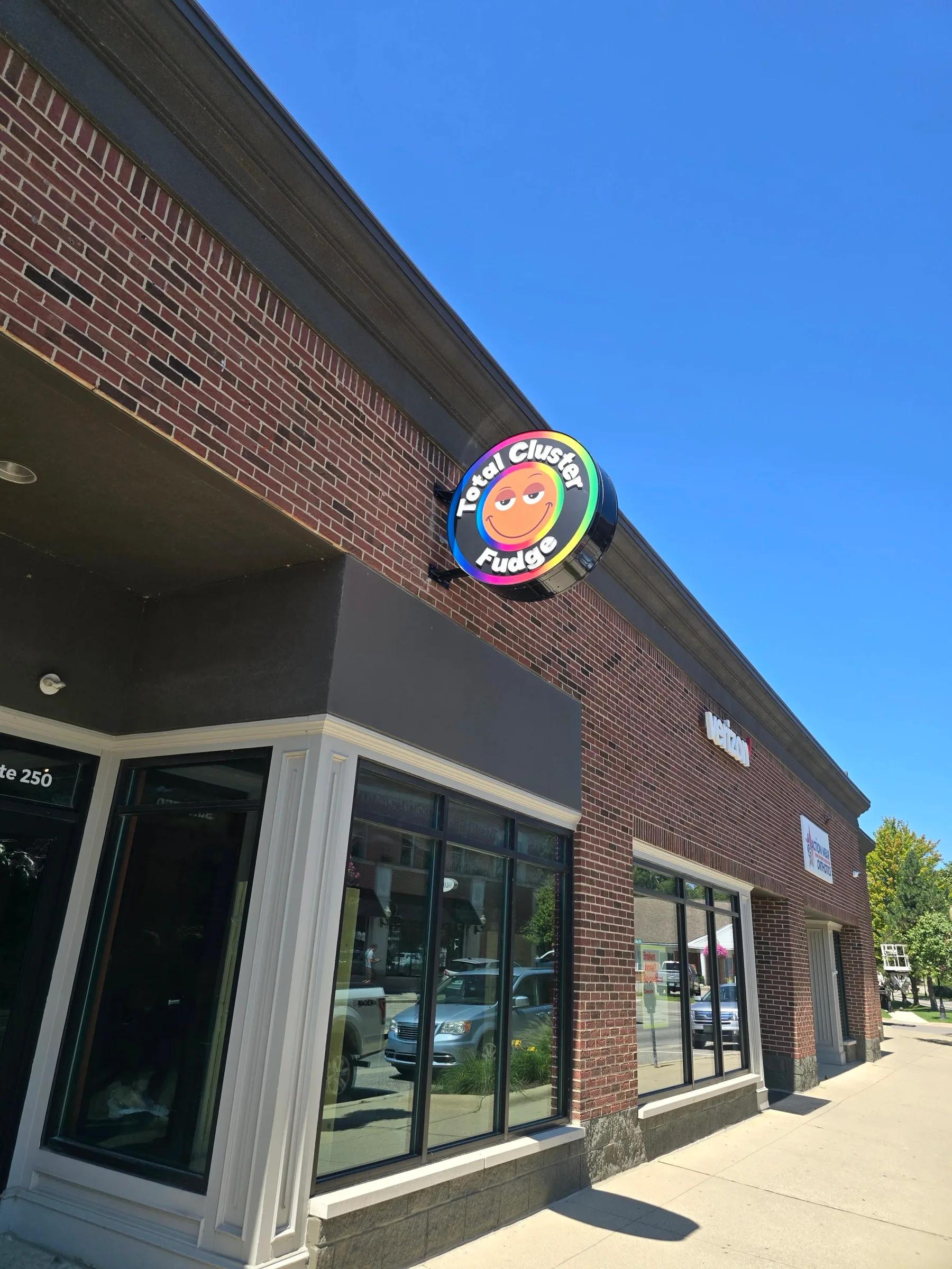 Round illuminated blade sign on the corner of a brick storefront