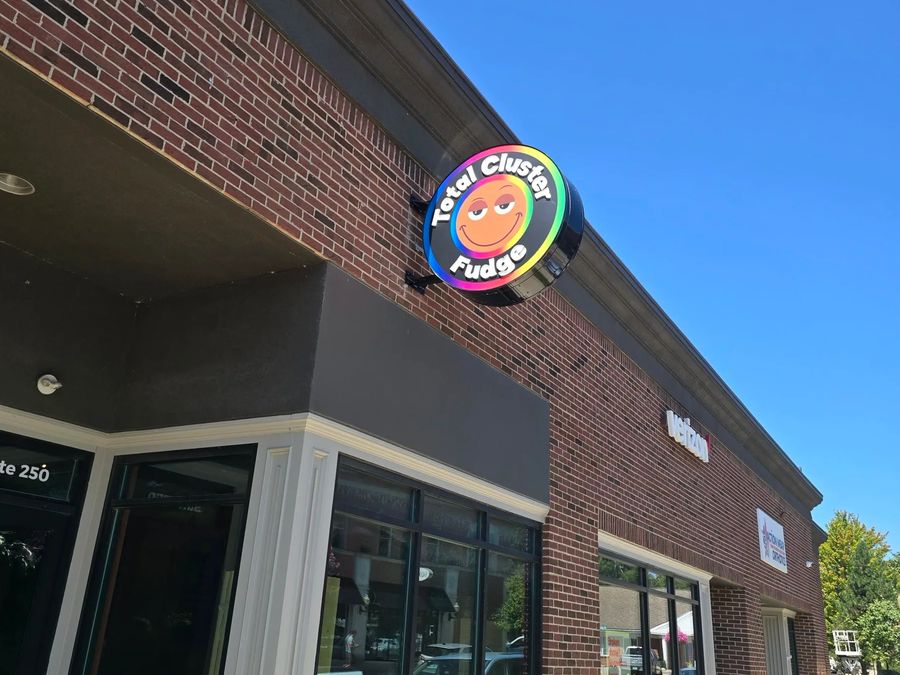 Round illuminated blade sign on the corner of a brick storefront