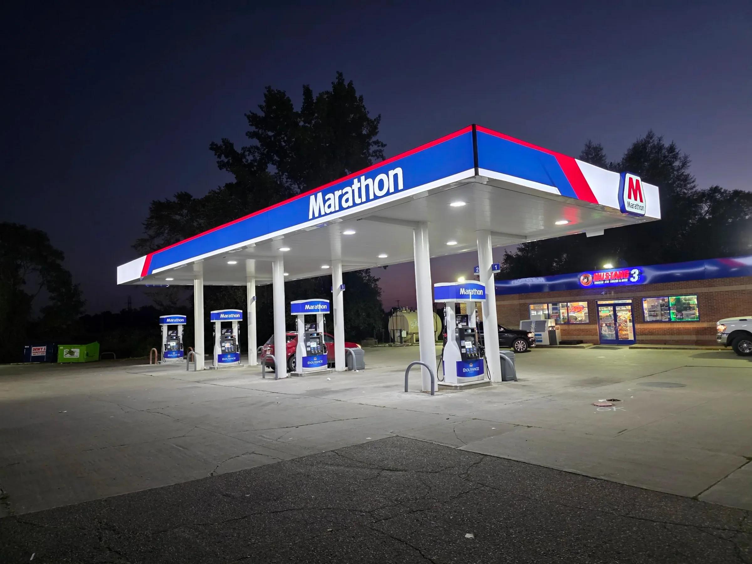 Marathon canopy with its blue and red fascia lit at night over branded dispensers