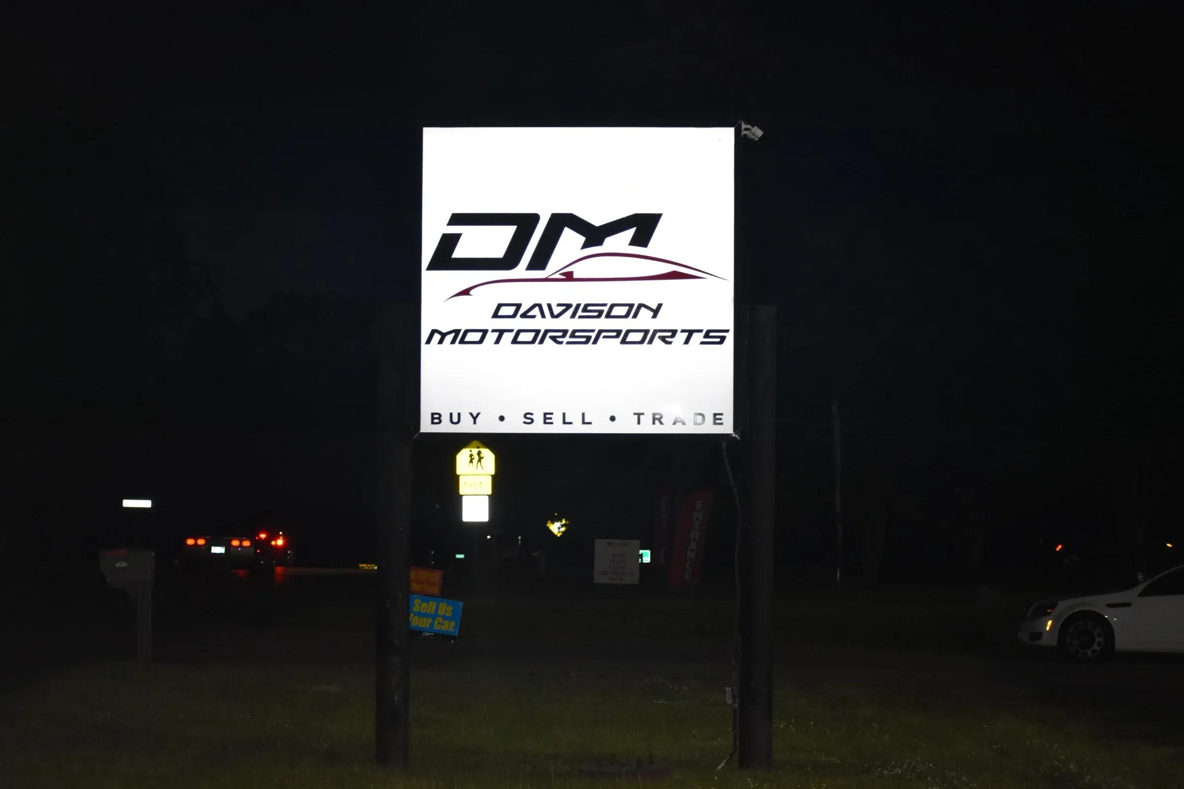 Davison Motorsports lit cabinet sign on a post at night