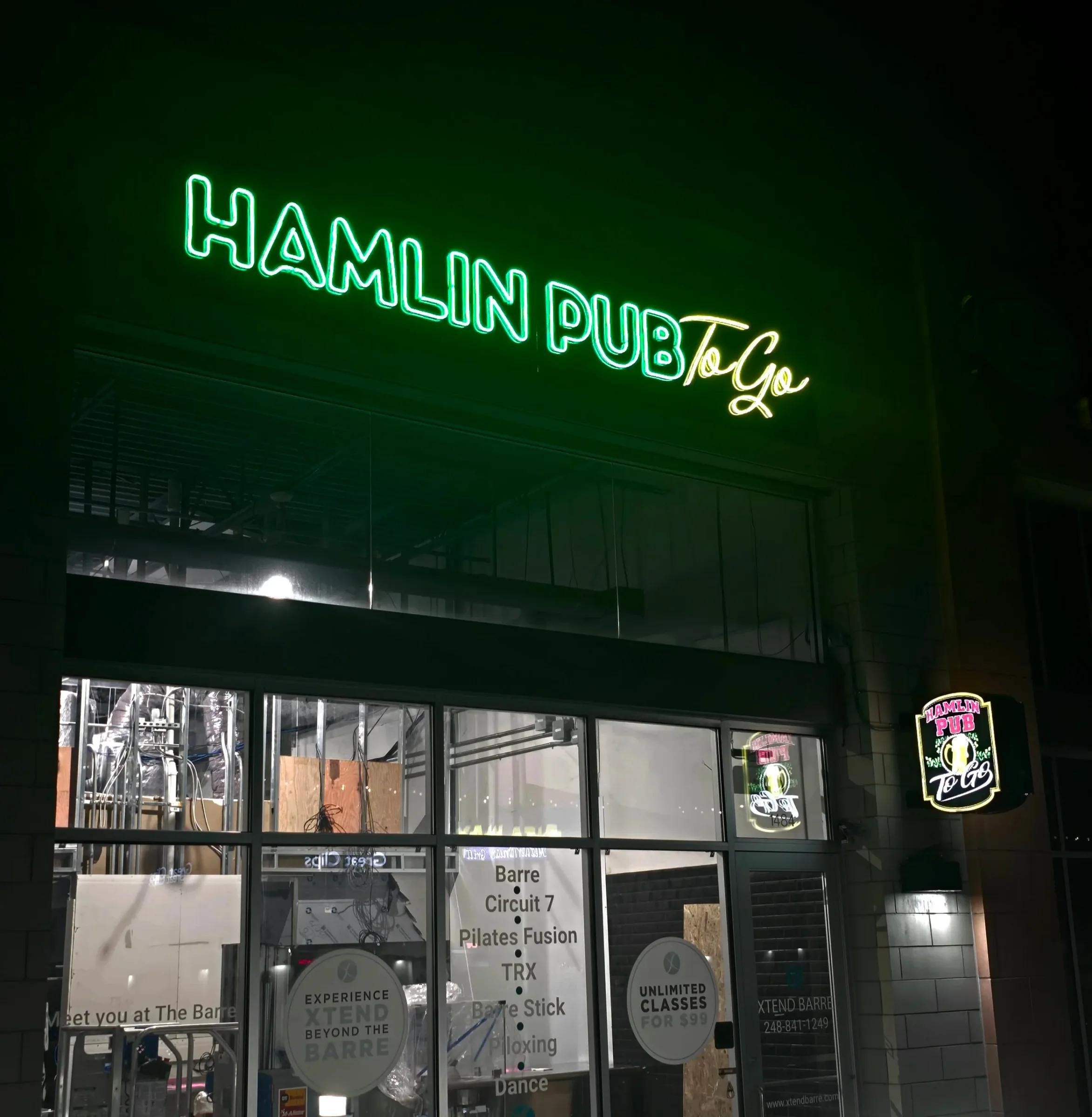 Hamlin Pub To Go letters glowing green over a storefront at night