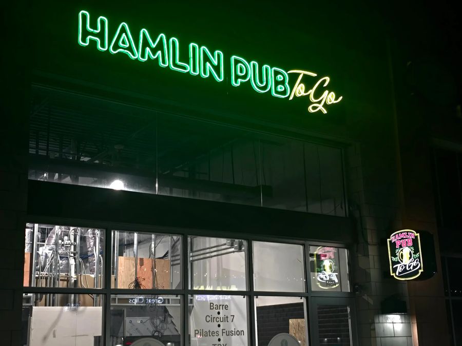 Hamlin Pub To Go letters glowing green over a storefront at night