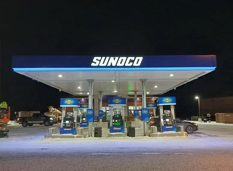 Sunoco canopy lit at night over a row of branded dispensers