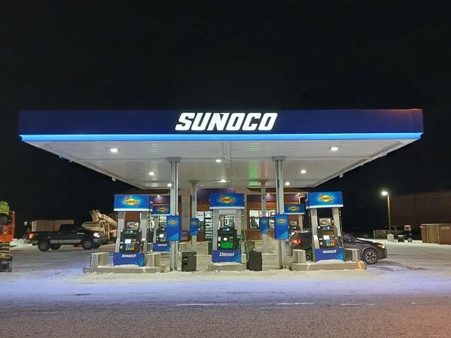 Sunoco canopy lit at night over a row of branded dispensers