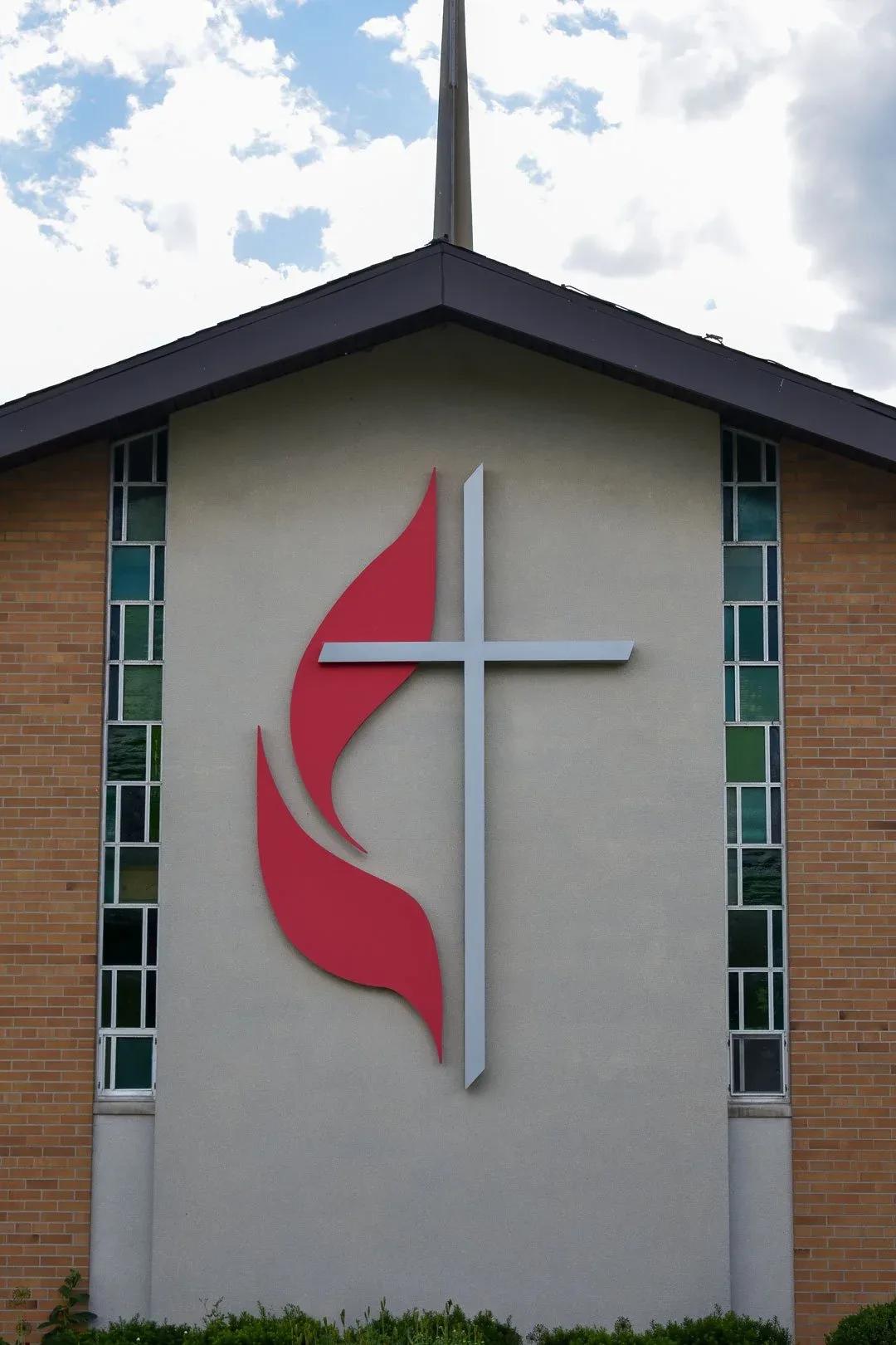 Red flame and cross emblem on a church front between tall windows