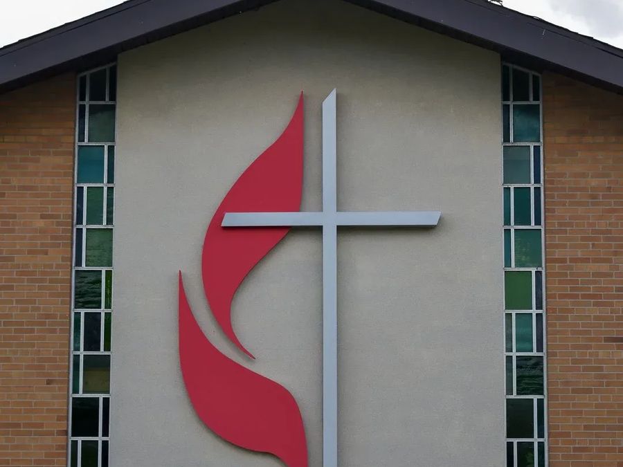 Red flame and cross emblem on a church front between tall windows