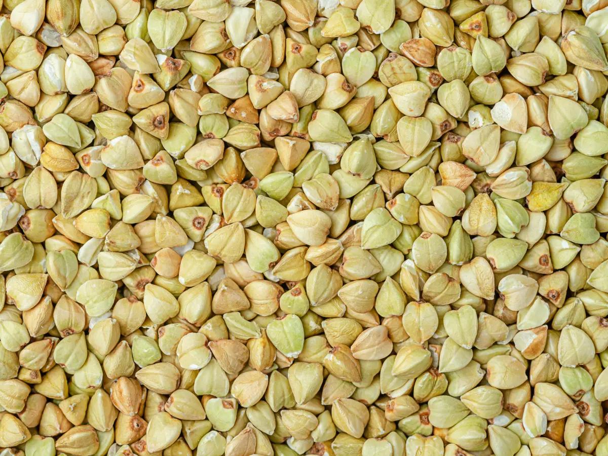 A close-up of clean, raw White Buckwheat Groats, showcasing their pale color and pyramid-like shape.