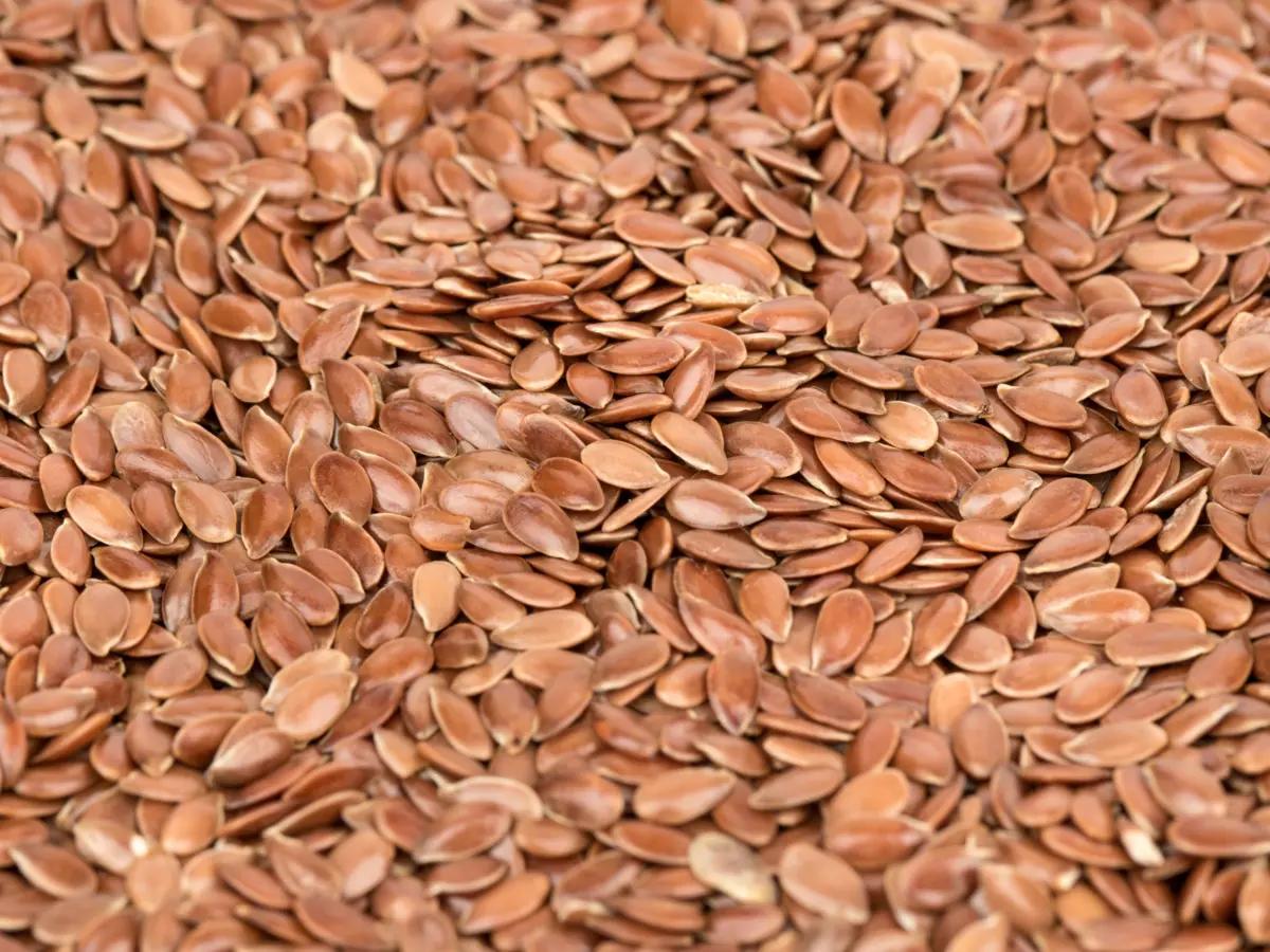 A close-up of rich, brown flax seeds, showcasing their deep color and smooth, shiny surface.
