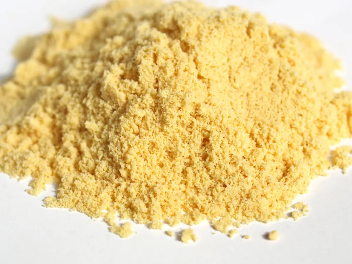 A minimalist pile of fine, bright yellow mustard powder on a clean white background, showcasing its pure texture.