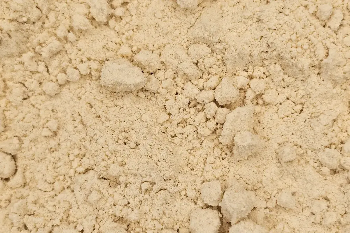 A mound of fine, pale yellow De-oiled Mustard Flour, showcasing its smooth texture.