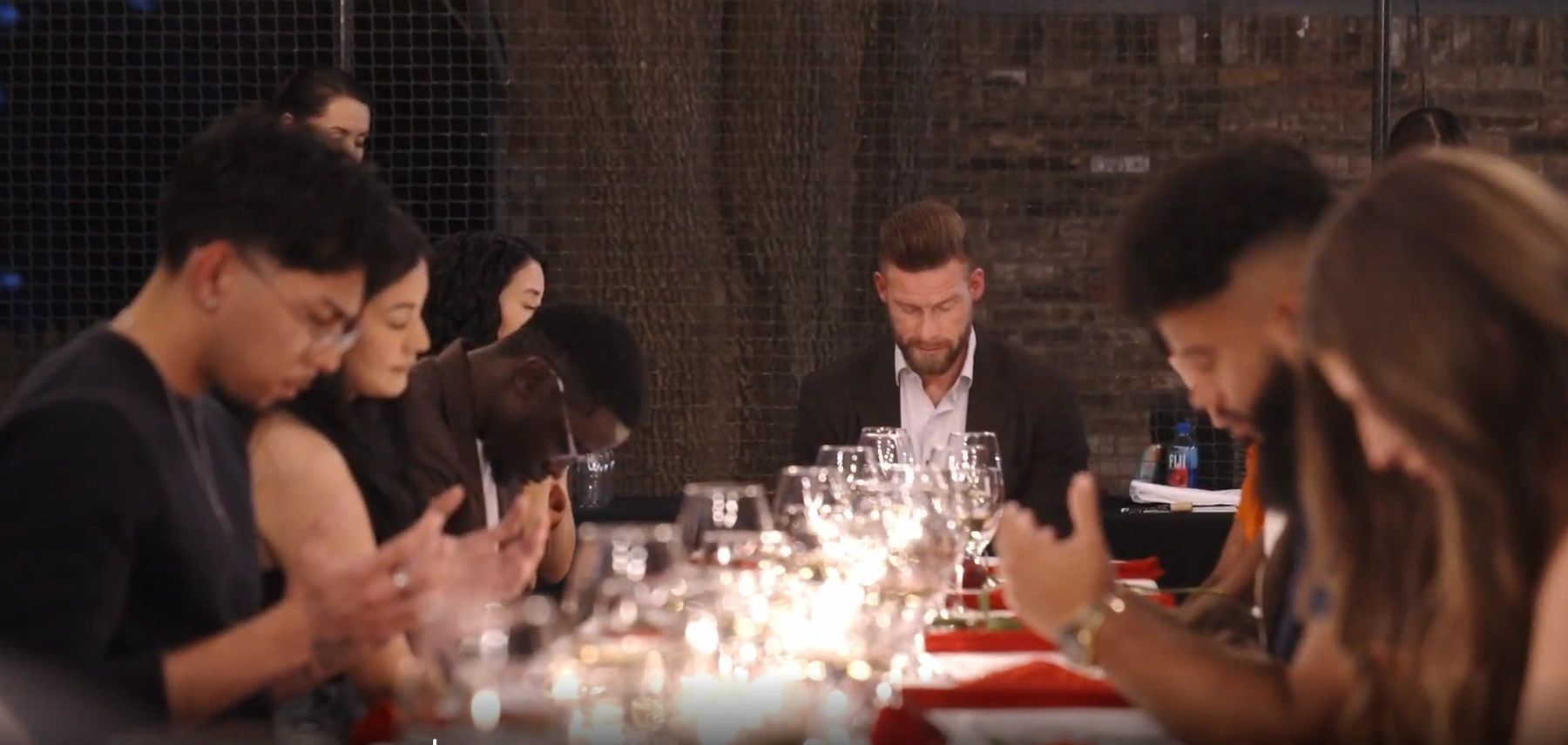 XVI guests bowing in prayer at the dinner table
