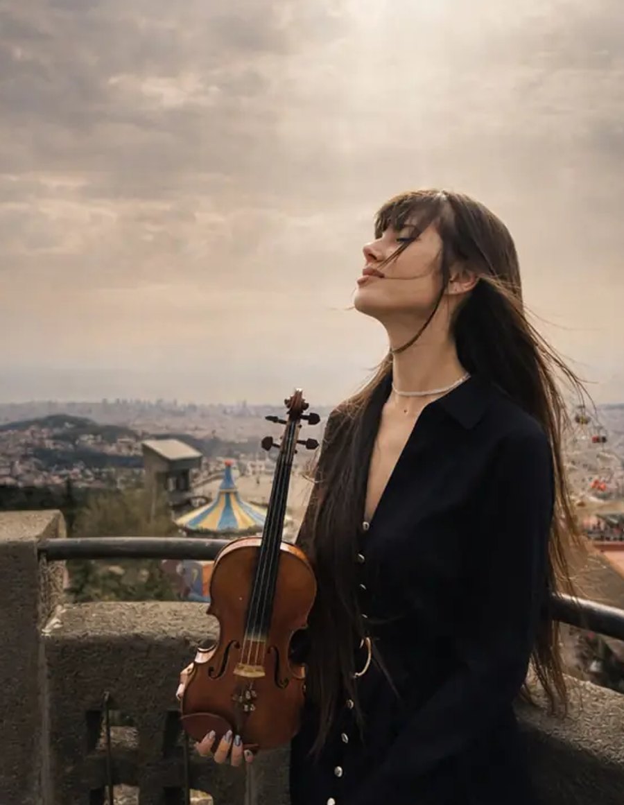 Astrid Torrente con violín en un mirador de Barcelona, con la ciudad al fondo
