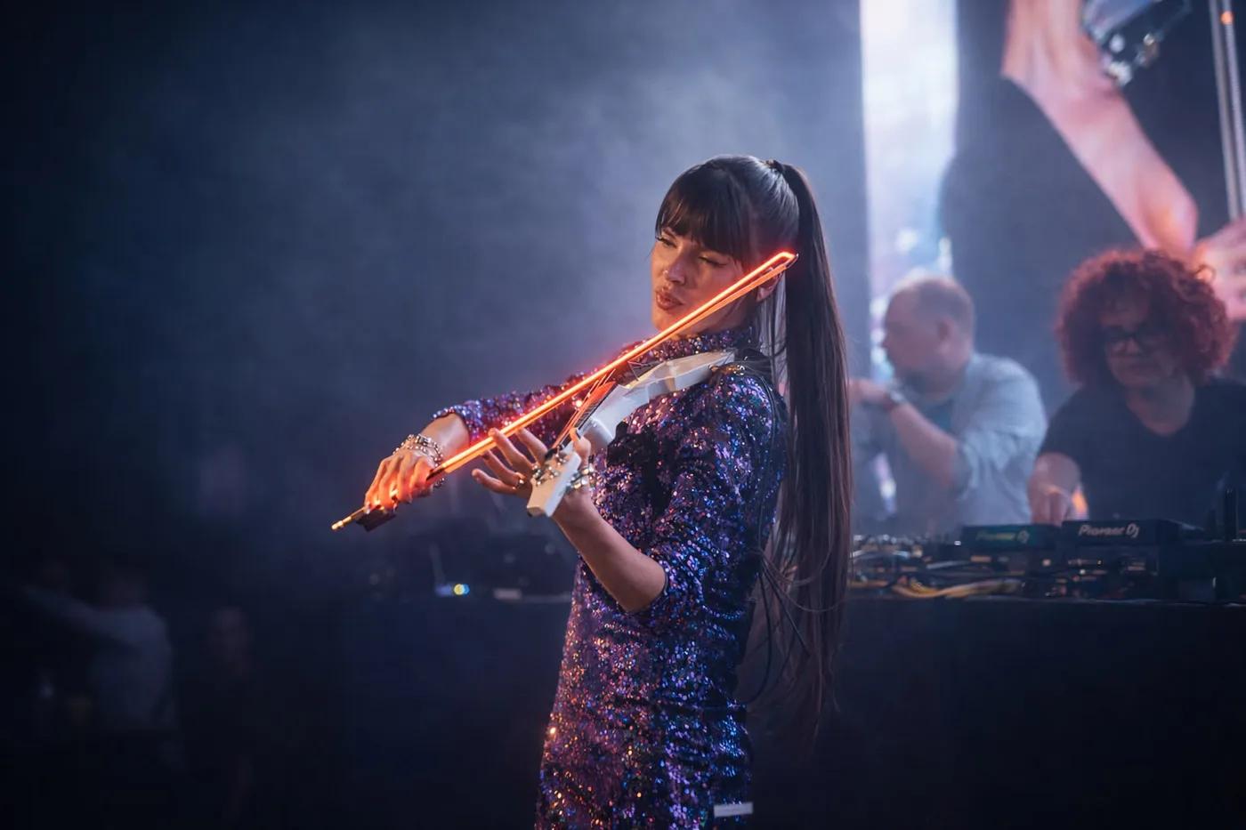 Astrid Torrente tocando el violín eléctrico LED en un evento nocturno