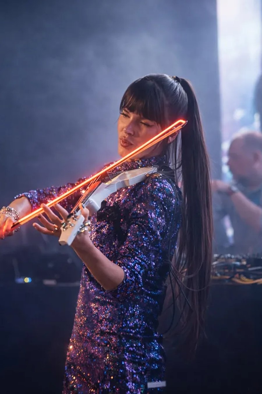 Astrid Torrente playing an LED electric violin at an evening event