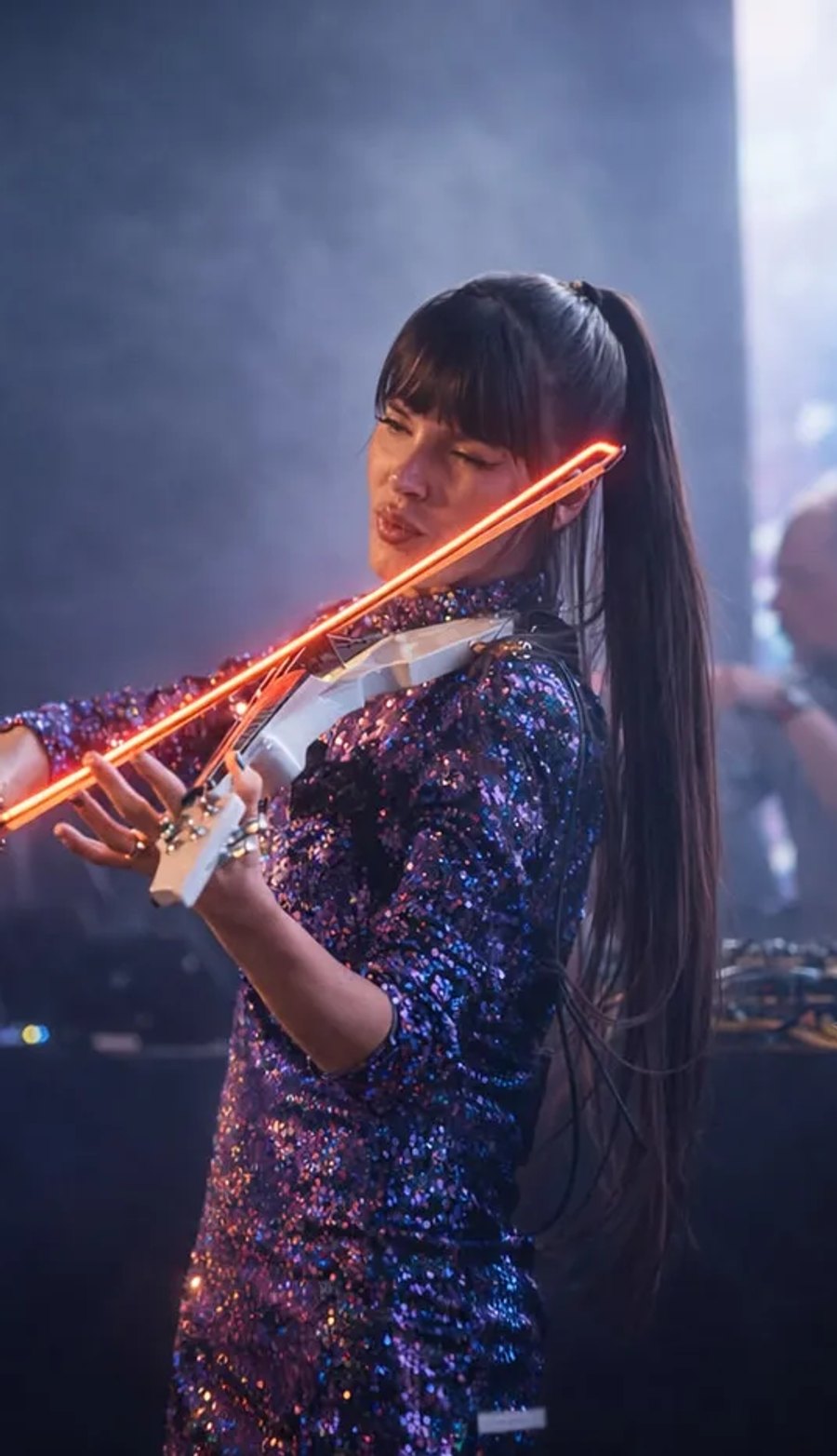 Astrid Torrente tocando el violín eléctrico LED en un evento nocturno