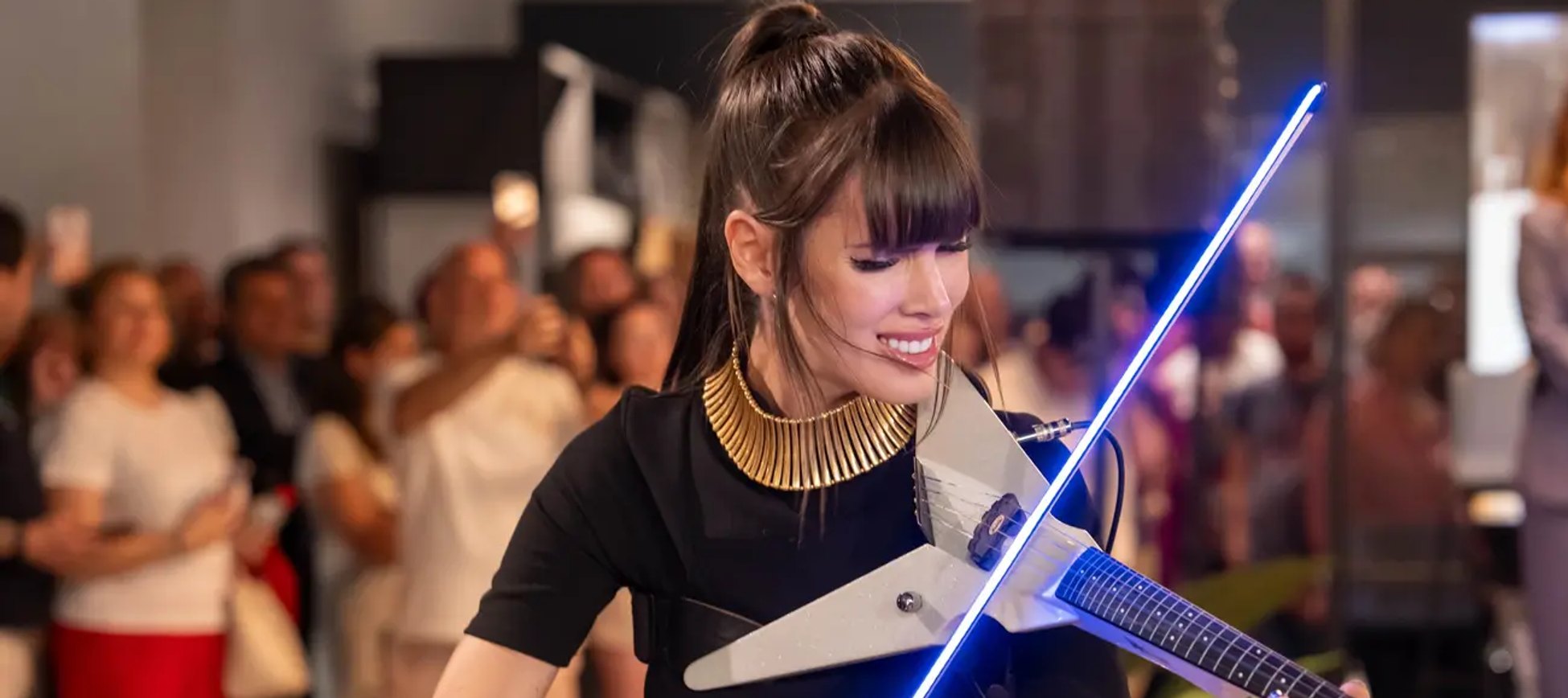 Astrid Torrente tocando un violín eléctrico con luz azul ante el público en un evento en directo.