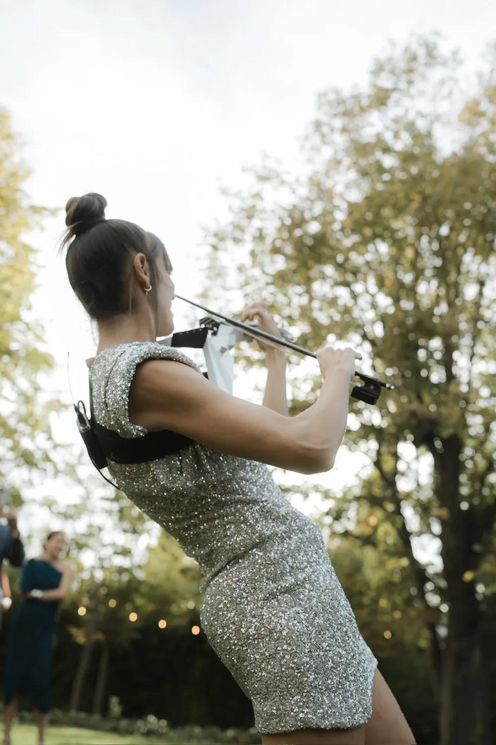 Astrid Torrente tocando el violín eléctrico durante la ceremonia al aire libre de una boda