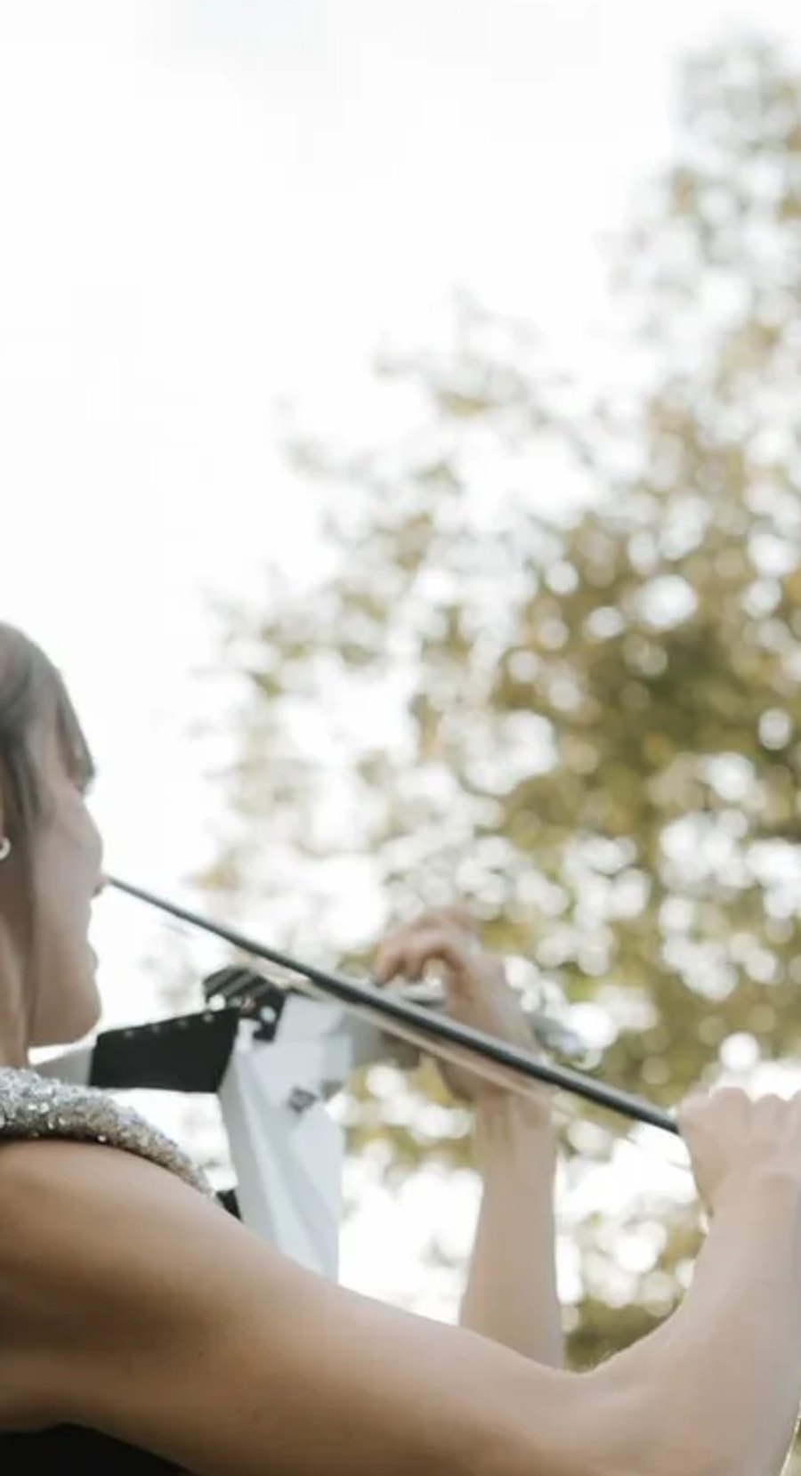 Astrid Torrente tocando el violín eléctrico durante la ceremonia al aire libre de una boda