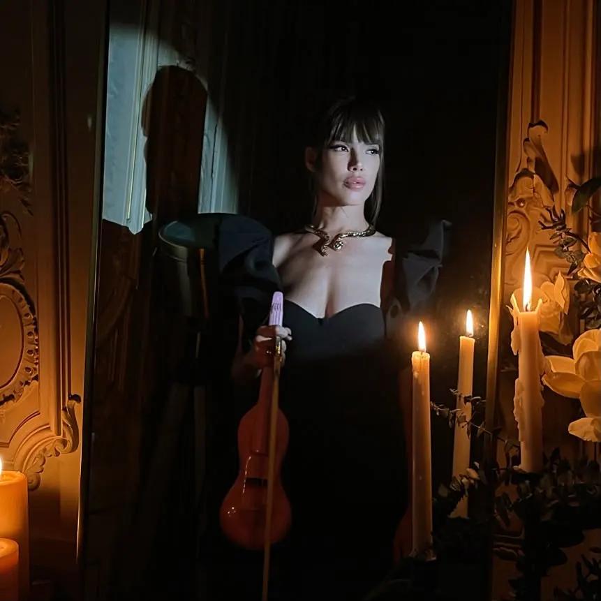 Retrato editorial de Astrid Torrente sosteniendo su violín junto a un espejo y velas.