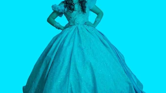 A person in a sparkly princess ball gown with hands on hips, against a teal background