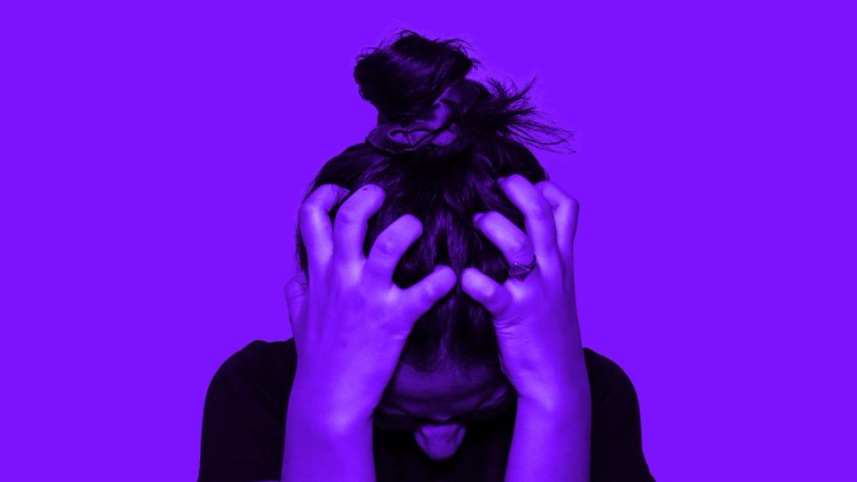 A person gripping their head in frustration against a purple background