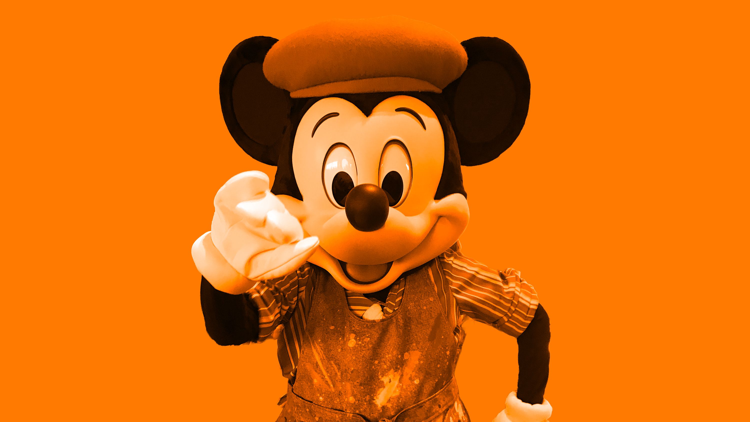 Mickey Mouse in a beret and artist's smock against an orange background