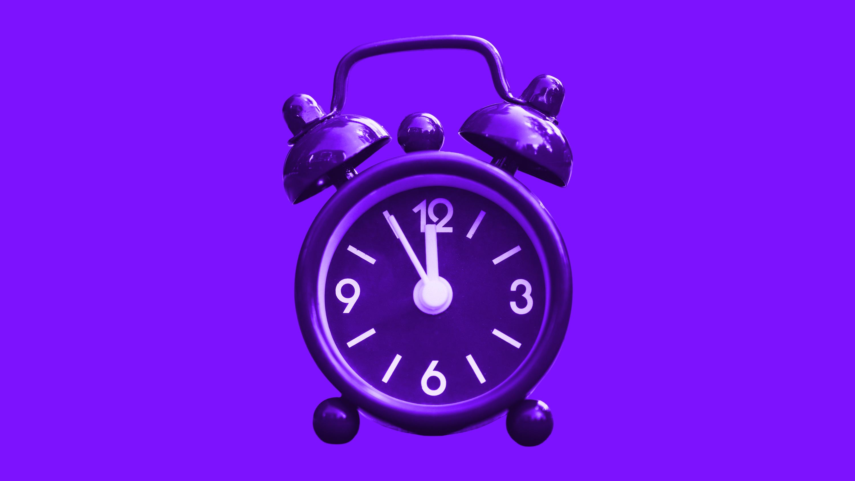 A vintage alarm clock tinted purple, its hands near twelve