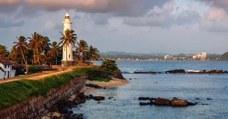 The lighthouse and coastal rampart of Galle Fort at sunset