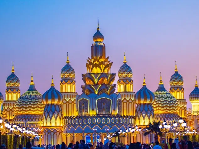 Golden onion-domed pavilion at Dubai Global Village under a glowing sky.