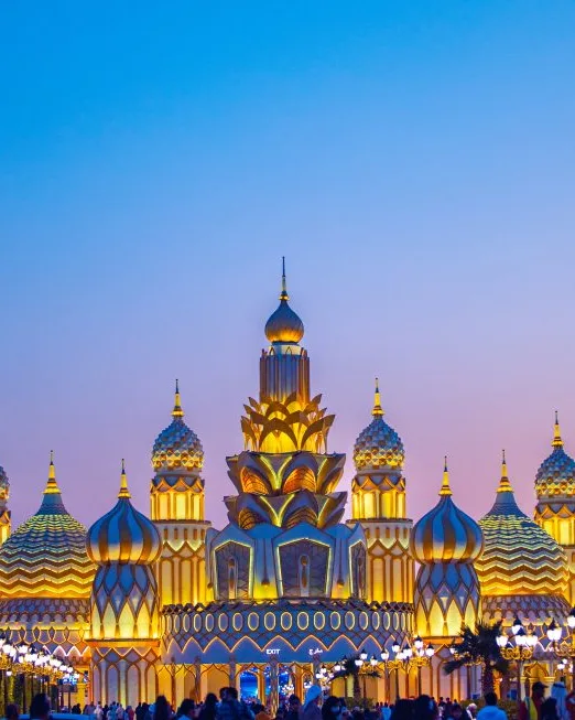 Golden onion-domed pavilion at Dubai Global Village under a glowing sky.
