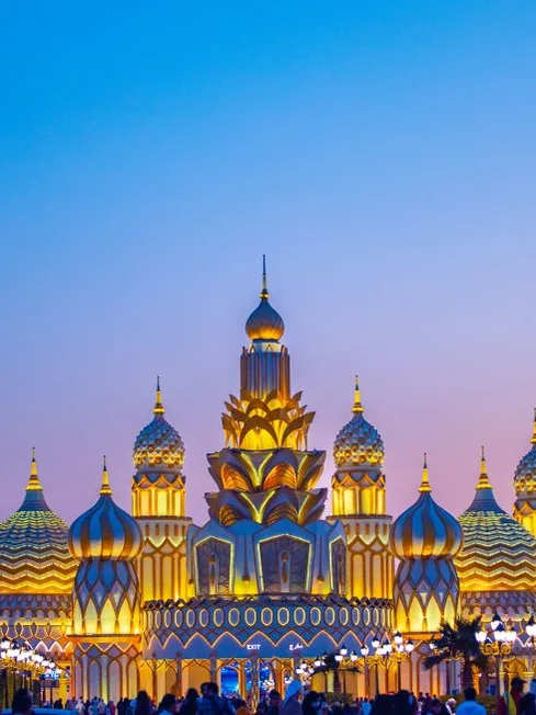 Golden onion-domed pavilion at Dubai Global Village under a glowing sky.