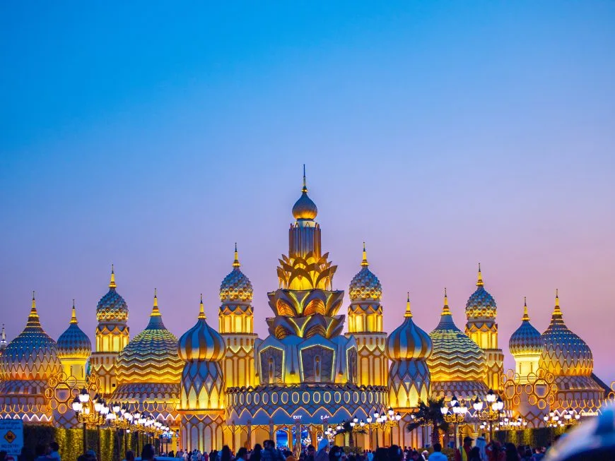 Golden onion-domed pavilion at Dubai Global Village under a glowing sky.