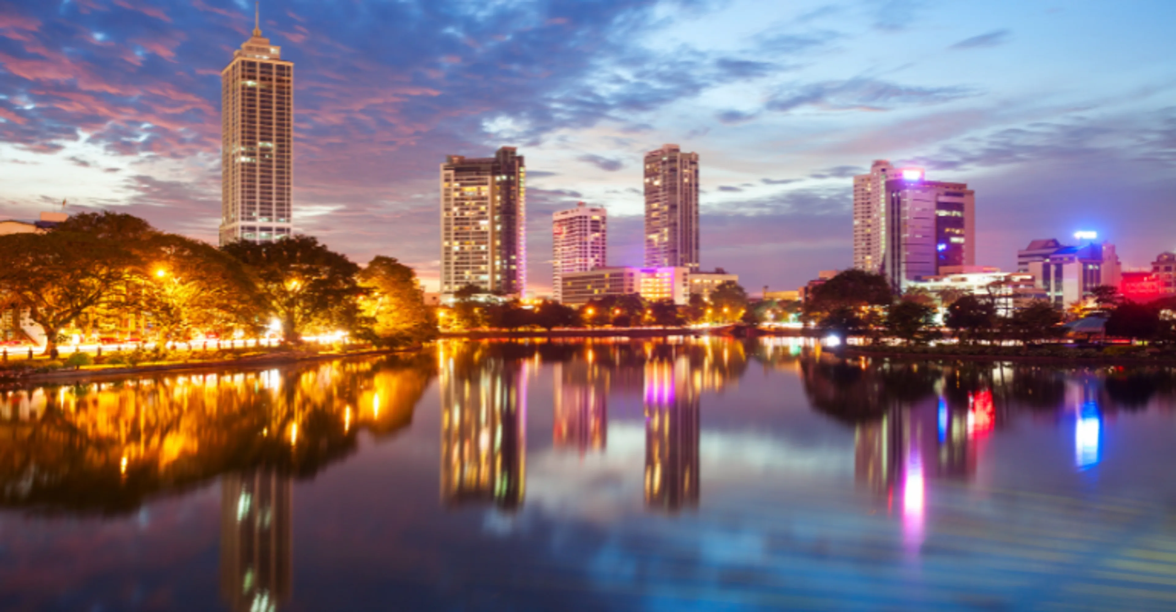 Colombo's skyline lit up at dusk, reflected in Beira Lake