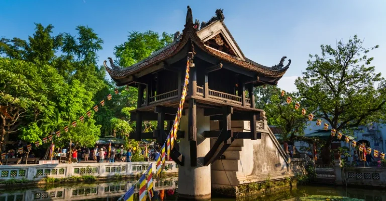 The One Pillar Pagoda on stilts above a lotus pond in Hanoi, decorated with colorful prayer flags