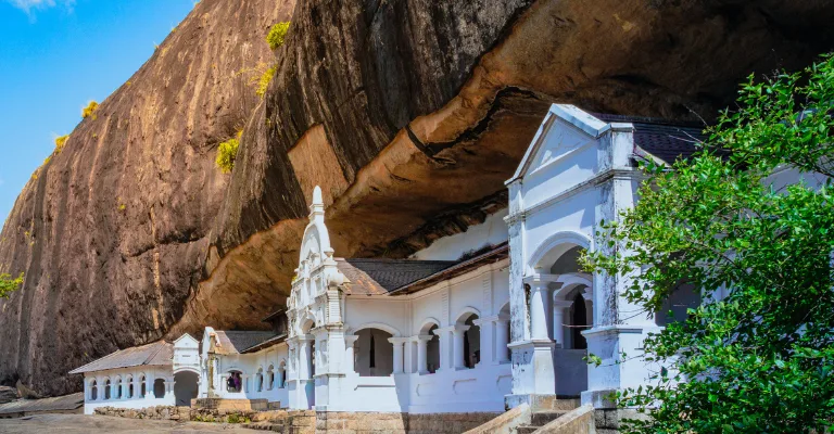 The whitewashed shrines of the Dambulla Cave Temple built into the rock overhang