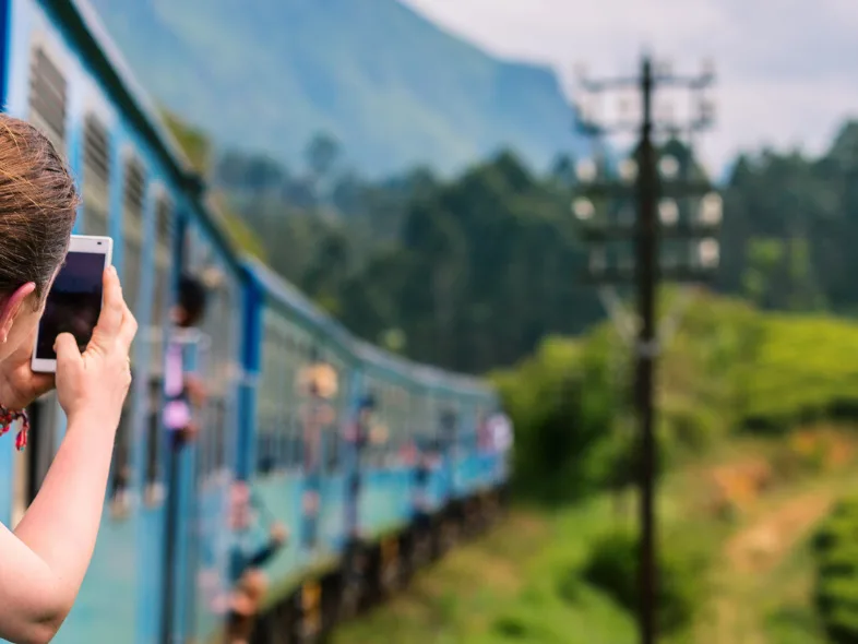 A traveler photographing tea plantations from a train window in Sri Lanka's hill country