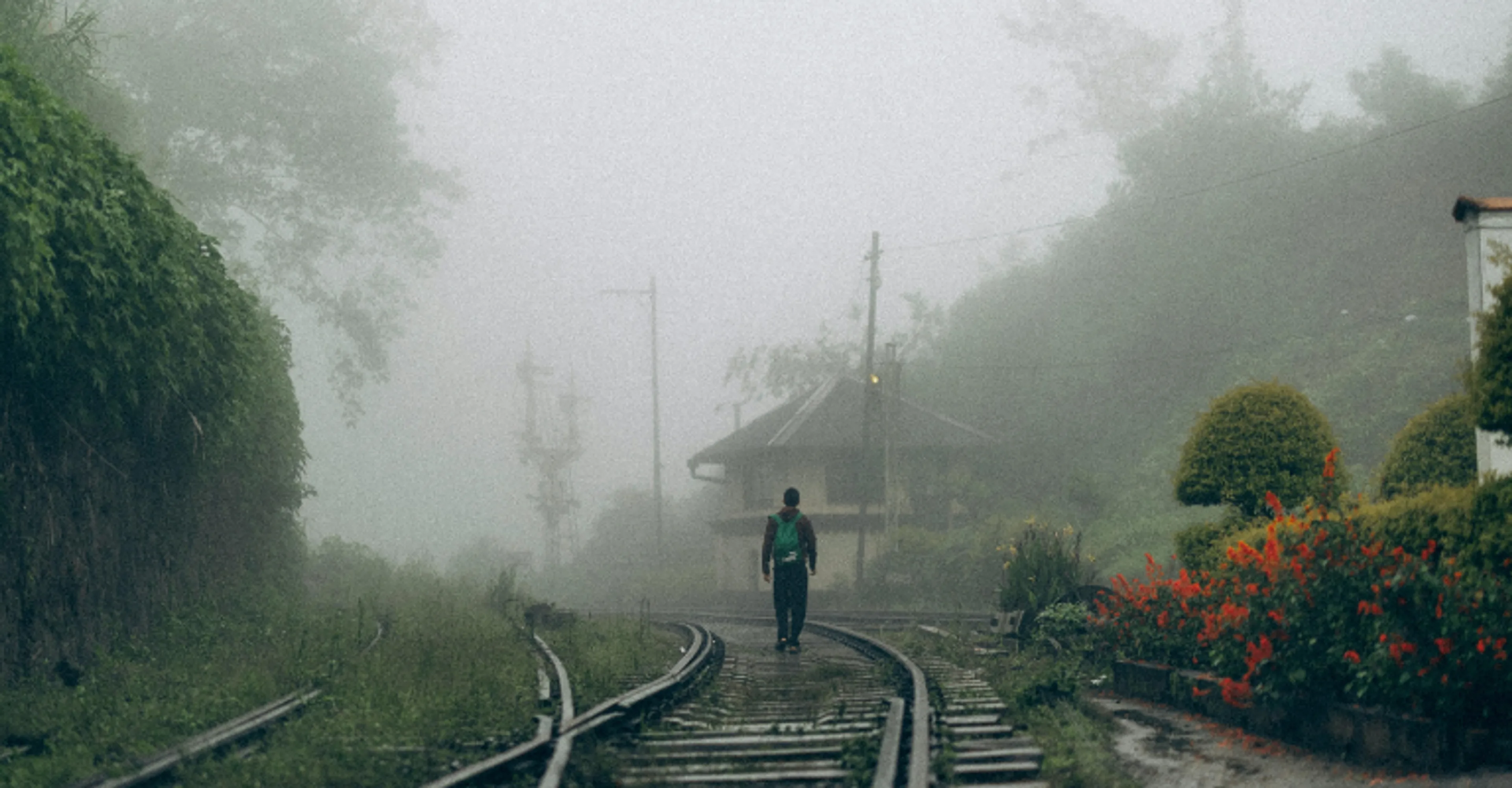 A misty, rain-soaked railway track and hill-country station in Sri Lanka