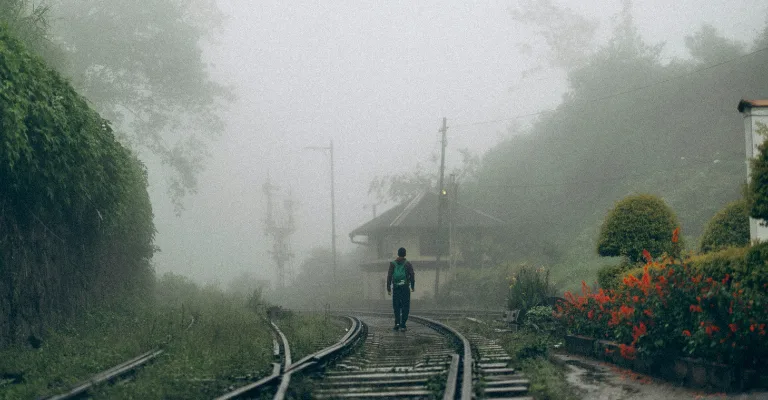 A misty, rain-soaked railway track and hill-country station in Sri Lanka