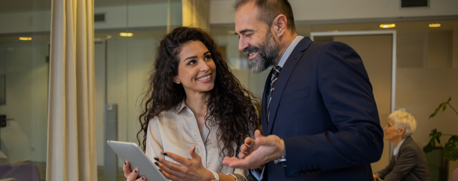 Businesswoman and businessman having a friendly conversation while holding a tablet