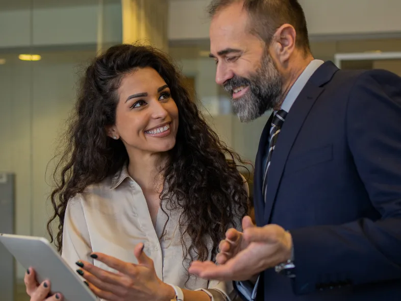Businesswoman and businessman having a friendly conversation while holding a tablet